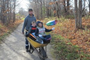 Man with two kids in wheelbarrow doing volunteer work